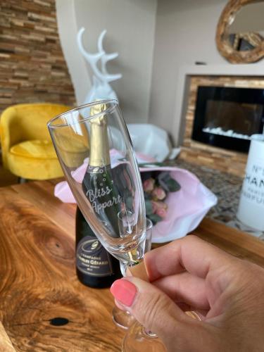 une personne tenant un verre de vin à côté d'une bouteille dans l'établissement Bliss’appart boulogne/mer logement avec balnéothérapie, à Boulogne-sur-Mer