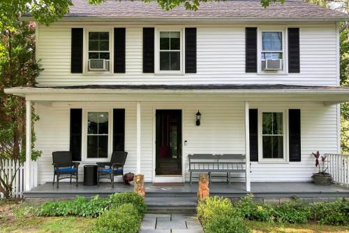 a white house with a porch with two chairs on it at Cozy Litchfield House with Fenced-In Yard and Fire Pit in Litchfield