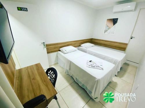 two beds in a room with a table and a tv at Hotel Trevo Caruaru in Caruaru