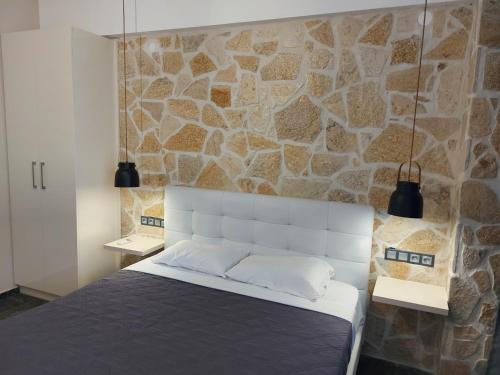 a bedroom with a stone wall and a bed at The Santo George Beach Resort in Amoudara Herakliou