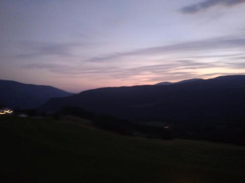 a view of a sunset from a field with mountains at La casa di Grace nella valle incantantata in Carano