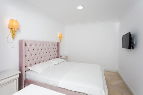 a bedroom with a white bed with a pink headboard at Apartament Amaya in Bistriţa