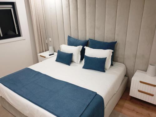 a bedroom with a large bed with blue and white pillows at Green Garden Houses in Chaves
