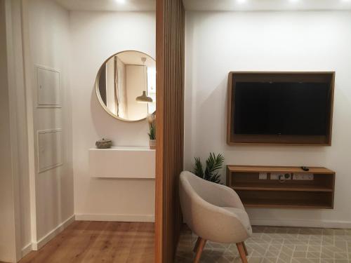 a living room with a television and a chair at Green Garden Houses in Chaves