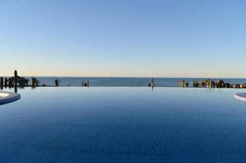 a large swimming pool with the ocean in the background at Encanto Living One Bedroom Unit by Kivoya in Puerto Peñasco