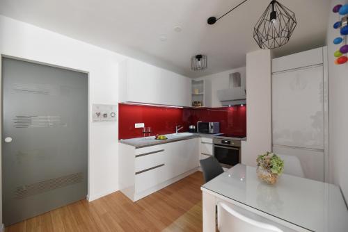 cocina con paredes rojas, armarios blancos y mesa en Mary's apartment - with free parking en Zagreb