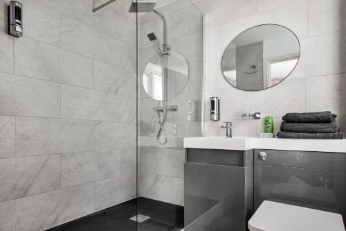 een badkamer met een douche, een wastafel en een spiegel bij Pink Sapphire Double Room with En-suite & Wifi in Derby