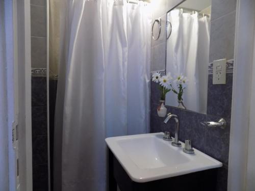 a bathroom with a sink and a white shower curtain at Hotel Embassy in Miramar
