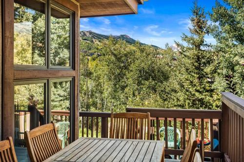 a table and chairs on a deck with a view of the mountains at Ridge 27 in Snowmass Village