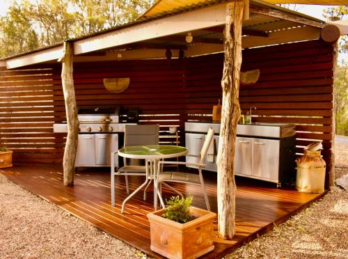 an outdoor kitchen with a table on a wooden deck at Ketchup's Bank Glamping in Boonah