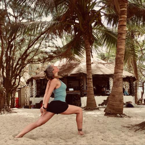 a woman doing a yoga pose on the beach at Jungle Beach Resort in Sanyang