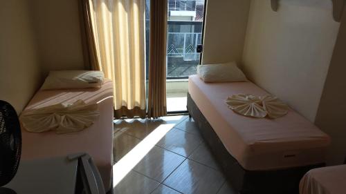 twee bedden in een kamer met een raam bij Casa e Suites in Aparecida