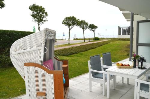 een patio met een tafel en stoelen en uitzicht op de oceaan bij Schloss am Meer - Whg3 große Terrasse mit Meerblick in Wyk auf Föhr