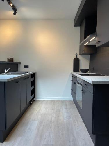 a kitchen with black cabinets and a wooden floor at Unique luxury apartment with cosy garden! in Ghent