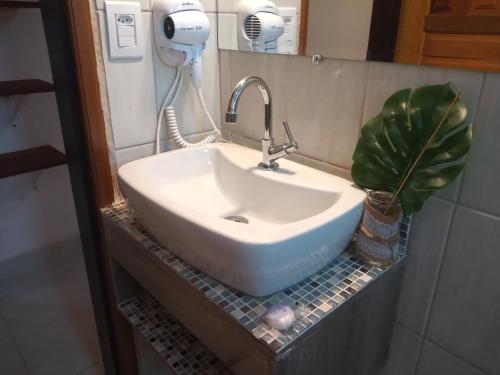 a white sink in a bathroom with a potted plant at Chalé de Charme Mandomai in Ilhabela