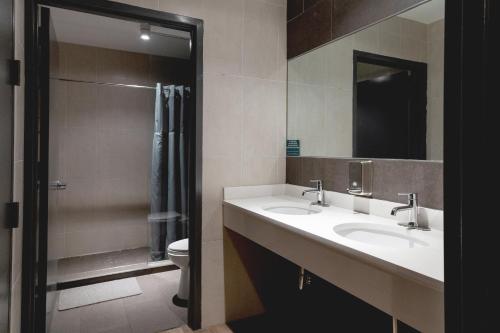 La salle de bains est pourvue de 2 lavabos et d'une douche. dans l'établissement Nap York Central Park Sleep Station, à New York