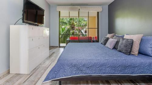een slaapkamer met een groot blauw bed en een tv bij 3rd-floor space with modern décor recently renovated viewing over pool in Coco in Coco