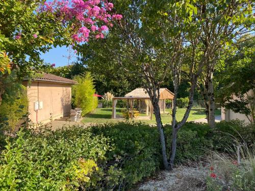 un jardin avec un kiosque et des fleurs roses dans l'établissement Le Piquet Résidence-Pavillon, à Cazaubon