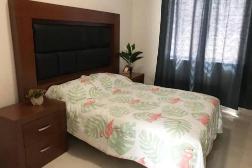 a bedroom with a bed and a dresser with a bedspread on it at Hermoso departamento con alberca in Manzanillo