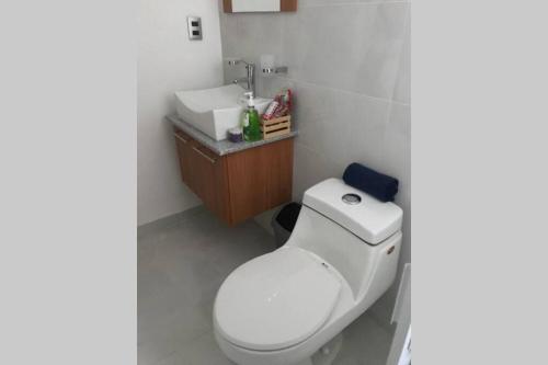 a bathroom with a white toilet and a sink at Hermoso departamento con alberca in Manzanillo