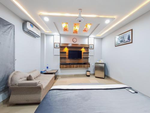 a room with a bed and a couch and a tv at Hotel Crown Inn Multan in Multan