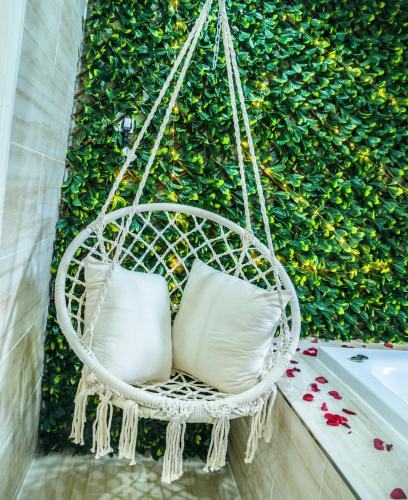 a hanging chair with two pillows in front of a hedge at Luxe bungalow Bradford in Wibsey