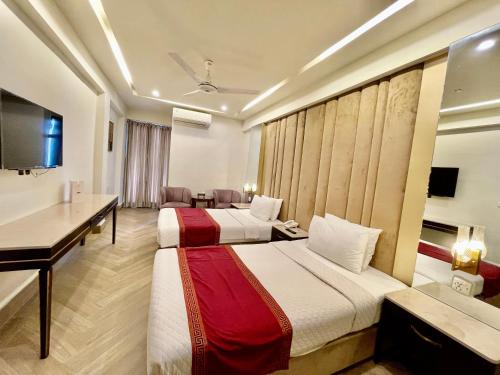 a hotel room with two beds and a desk at Shelton's Ambassador in Islamabad