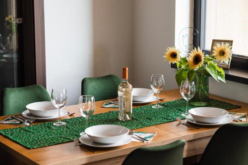 a wooden table with a bottle of wine and glasses at Bazalt Apartments in Miercurea-Ciuc