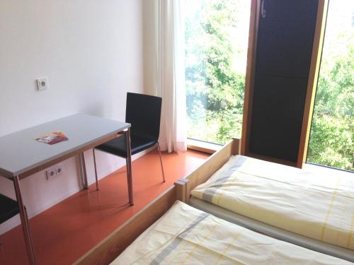a small room with a bed and a desk and a window at Jugendherberge Stuttgart Neckarpark in Stuttgart