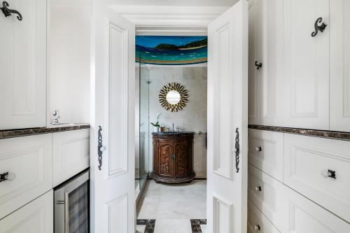 a kitchen with white cabinets and a mirror at Tusan Villa Little Manly in Sydney