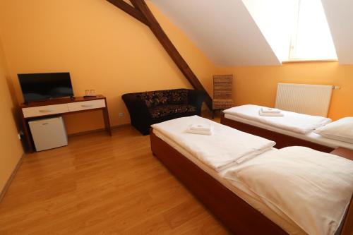 a room with two beds and a tv and a chair at Blatenský dvůr in Pardubice