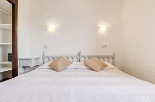 una camera con un letto bianco con due cuscini di Sobre de Granadella Haus 3-bis a Jávea