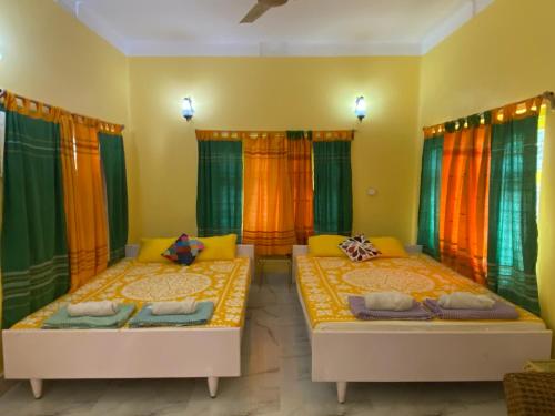 Nayantara في بولبور: سريرين في غرفة مع ستائر ملونة