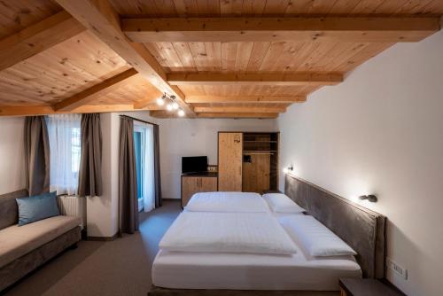 Habitación con 2 camas y sofá. en Hotel Monte44 en Selva di Val Gardena