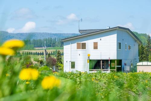 a white house in a field of flowers at The Landscape in Kami-furano