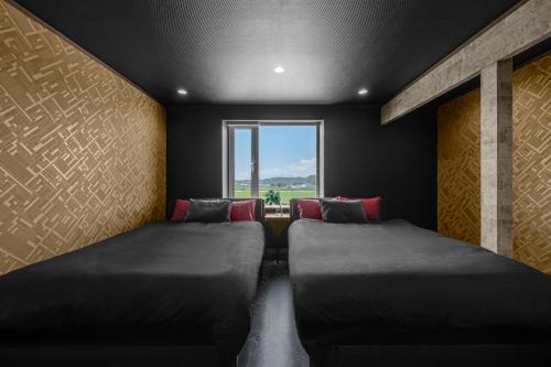 two beds in a room with a window at The Landscape in Kami-furano
