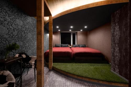 a bedroom with a large red bed with a green rug at The Landscape in Kami-furano
