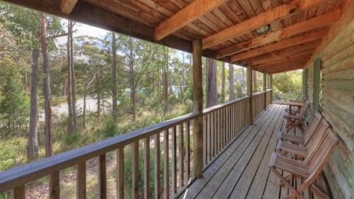 a porch of a cabin with two benches at Stewarts Bay Lodge in Port Arthur