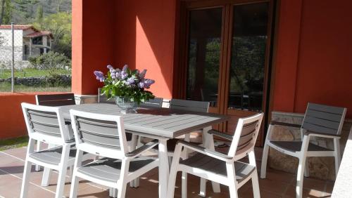 a wooden table with white chairs and a vase of flowers at Casa Rural Las Canales in Zapardiel de la Ribera