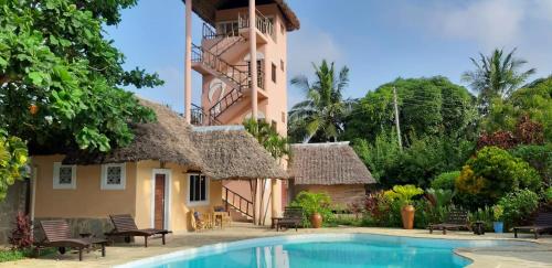 a hotel with a swimming pool in front of a building at Luxury Villa SOLEIL, Galu Diani Beach in Diani Beach