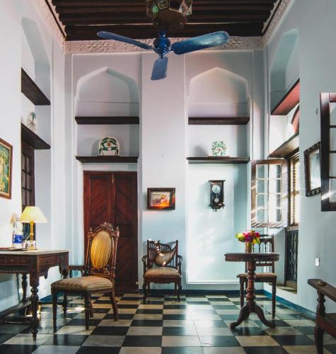 a living room with two chairs and a ceiling fan at Emerson on Hurumzi in Zanzibar City