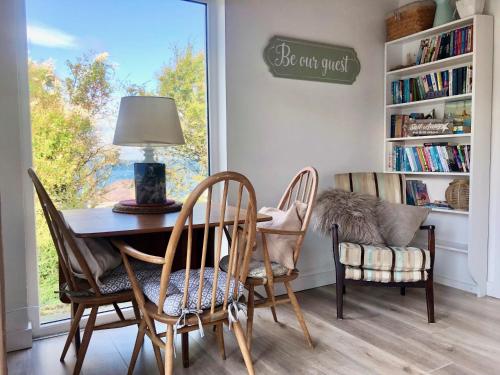 a dining room with a table and chairs and a window at Ballygally Seaview and Garden Hideaway in Ballygalley