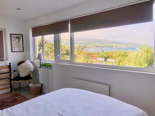 a bedroom with a large window with a view at Ballygally Seaview and Garden Hideaway in Ballygalley