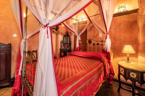 a bedroom with a canopy bed with red sheets at Emerson on Hurumzi in Zanzibar City