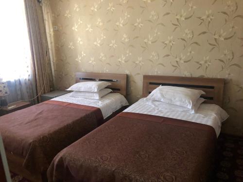 two beds in a room with a wall with flowers at Hello Dushanbe Guest House in Dushanbe