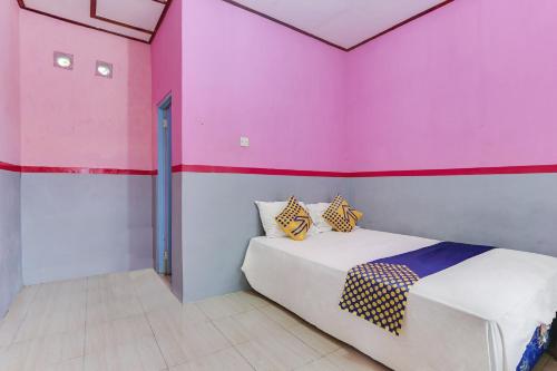 Habitación con cama con pared de color rosa en Ijen Traveller & Homestay en Banyuwangi