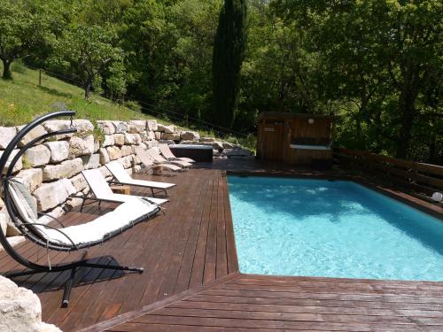 une piscine avec des chaises et une terrasse en bois dans l'établissement Le Cypressat, à Les Plans