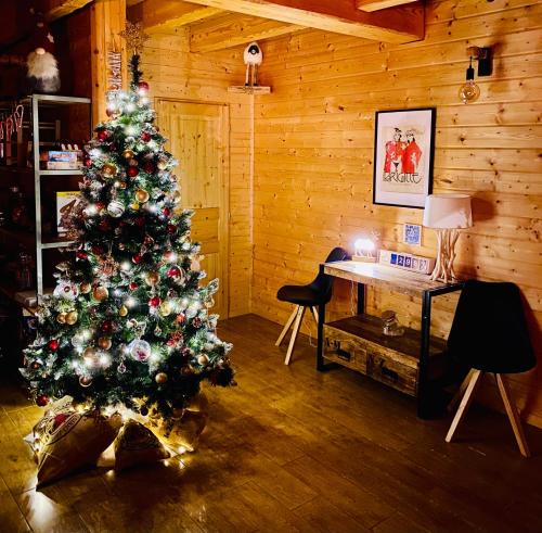 a christmas tree in a room with a desk at Le Hygge Chalet Gérardmer-Spa in Anould