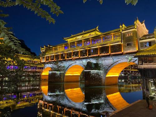 a bridge over a river in a city at night at Hemu House in Fenghuang