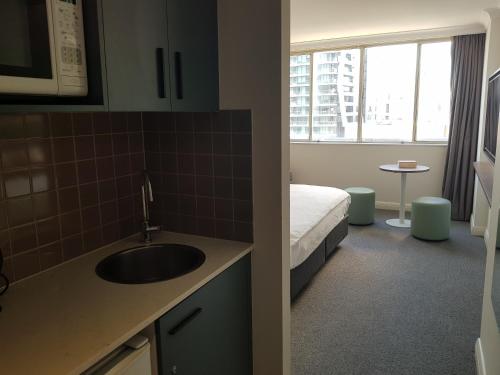 a bathroom with a sink and a bed in a room at Chatswood Hotel Apartment in Sydney